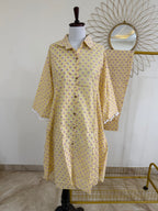 Yellow patterned dress on a mannequin with a decorative mirror in the background
