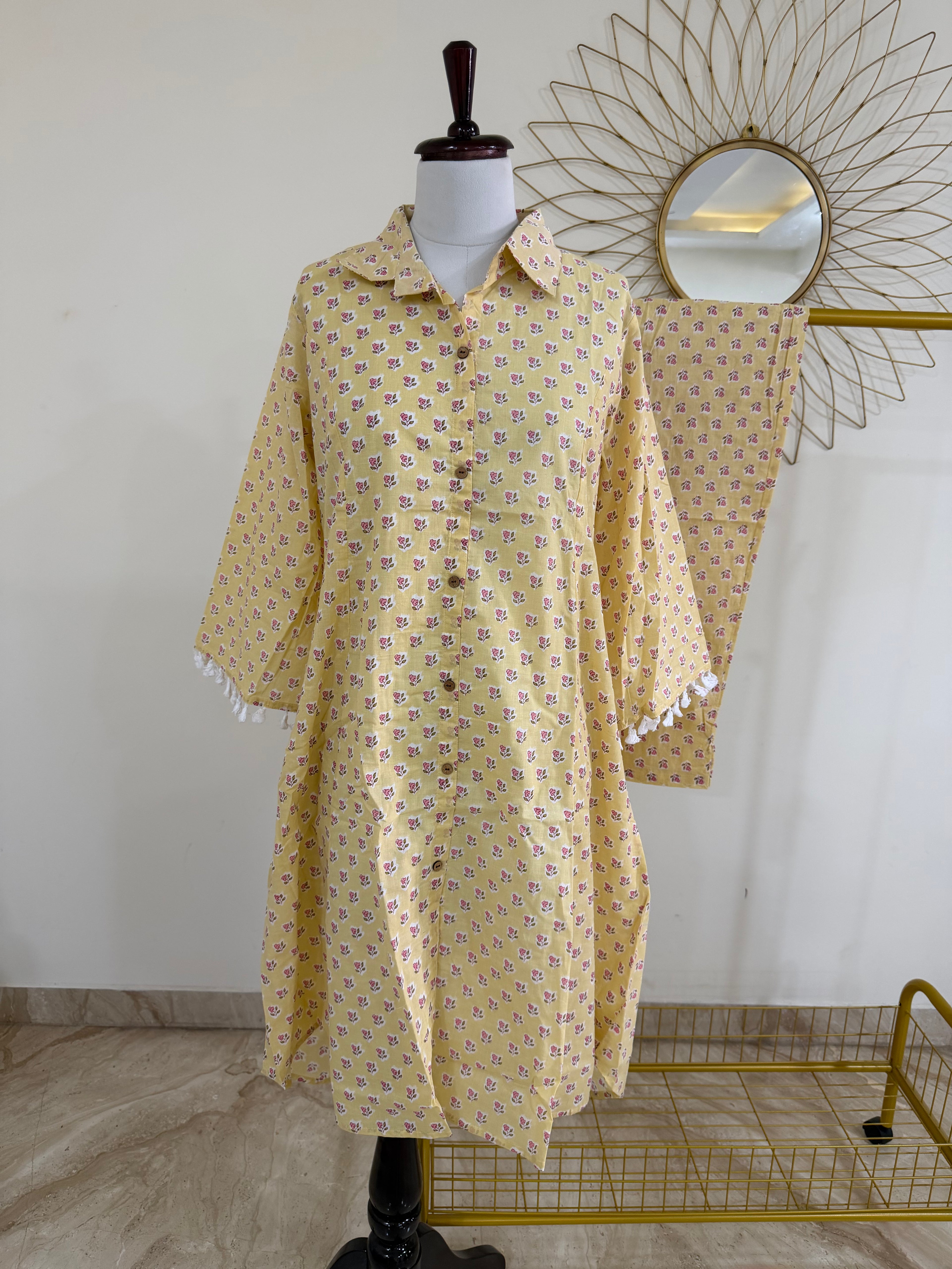 Yellow patterned dress on a mannequin with a decorative mirror in the background