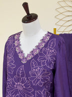 A purple long-sleeve tunic top with white floral embroidery and a scalloped embroidered neckline, displayed on a white mannequin torso.